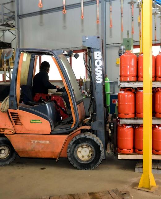 Gabelstapler transportiert eine Palette roter Propangasflaschen in der Lagerhalle von ZERZA Flüssiggas