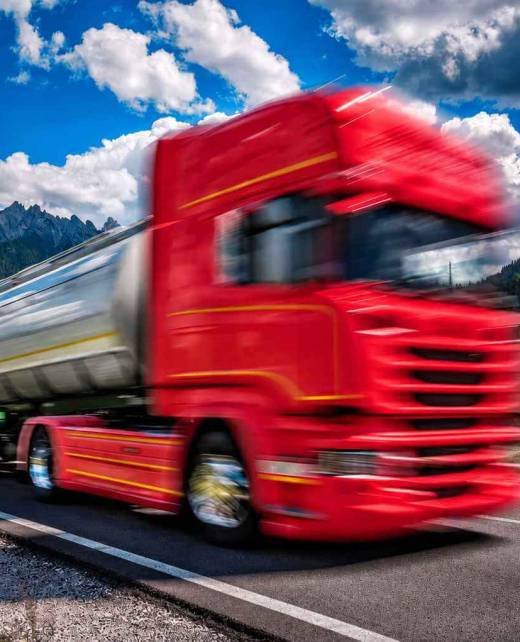 Roter Tanklastwagen auf einer Straße vor alpiner Berglandschaft